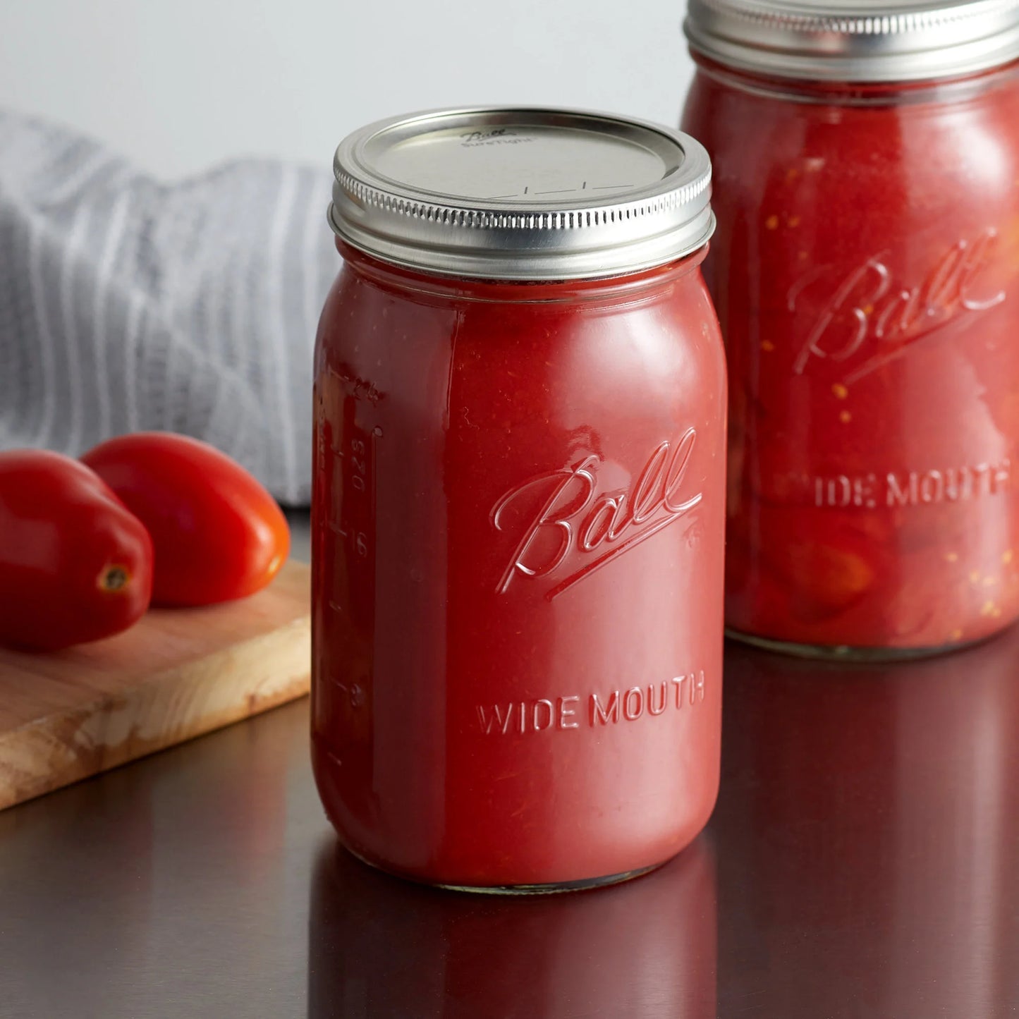 A pair of Ball canning jars filled with homemade tomato sauce on a kitchen counter