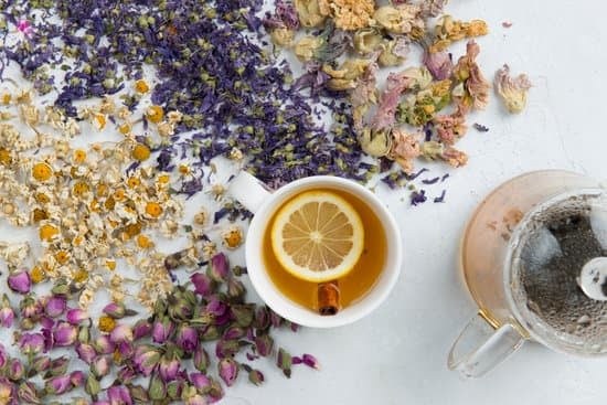 Herbs scattered on a white surface with a cup of brewed tea