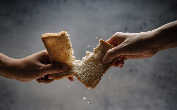 Two hands breaking a piece of bread