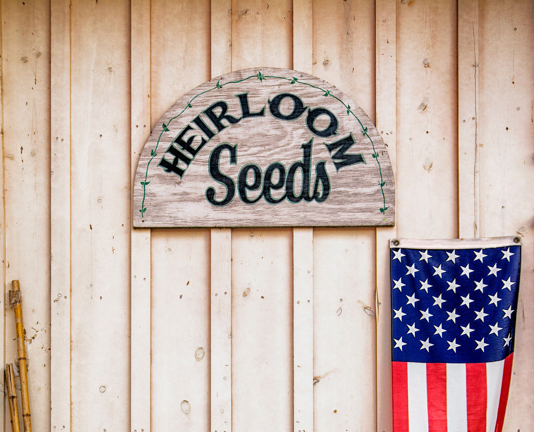 A sign stating heirloom seeds with an American flag next to it