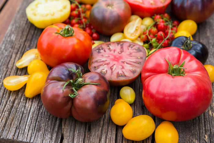 Different types of heirloom tomatoes laying on a wooden surface