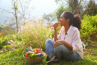 A woman eating freshly picked vegetables from a basket