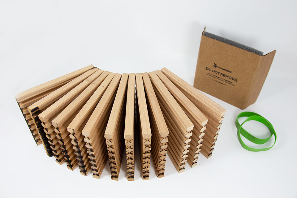 Stack of wooden mason bee trays unbound by green rubber bands