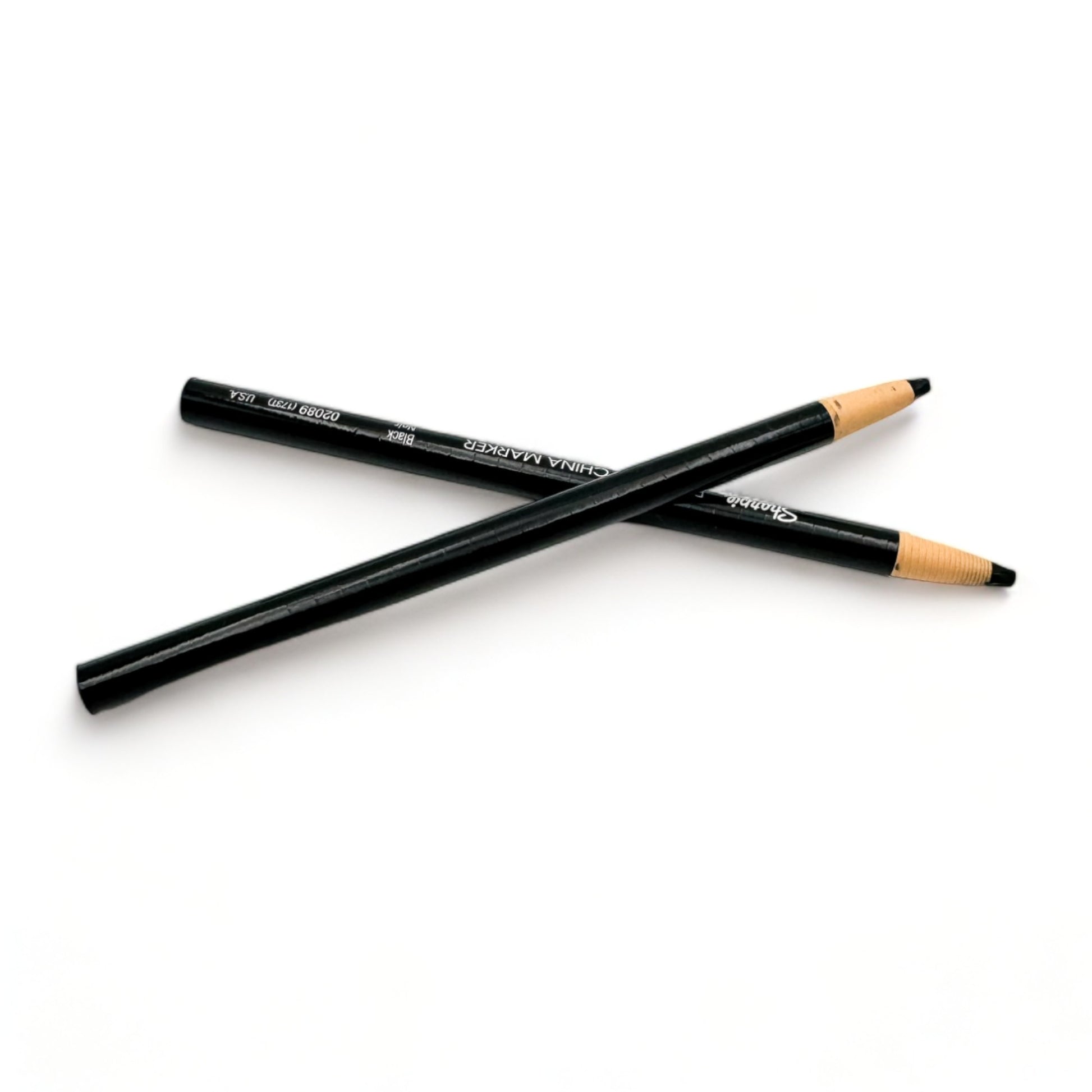 A pair of oil pencils for documenting presented on a clean white surface