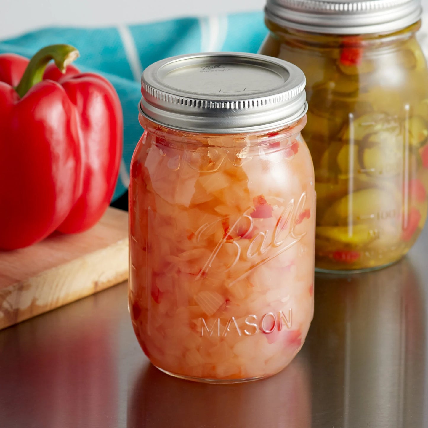 A duo of Ball jars packed with pickled vegetables on a kitchen surface