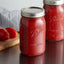 A pair of Ball canning jars filled with homemade tomato sauce on a kitchen counter