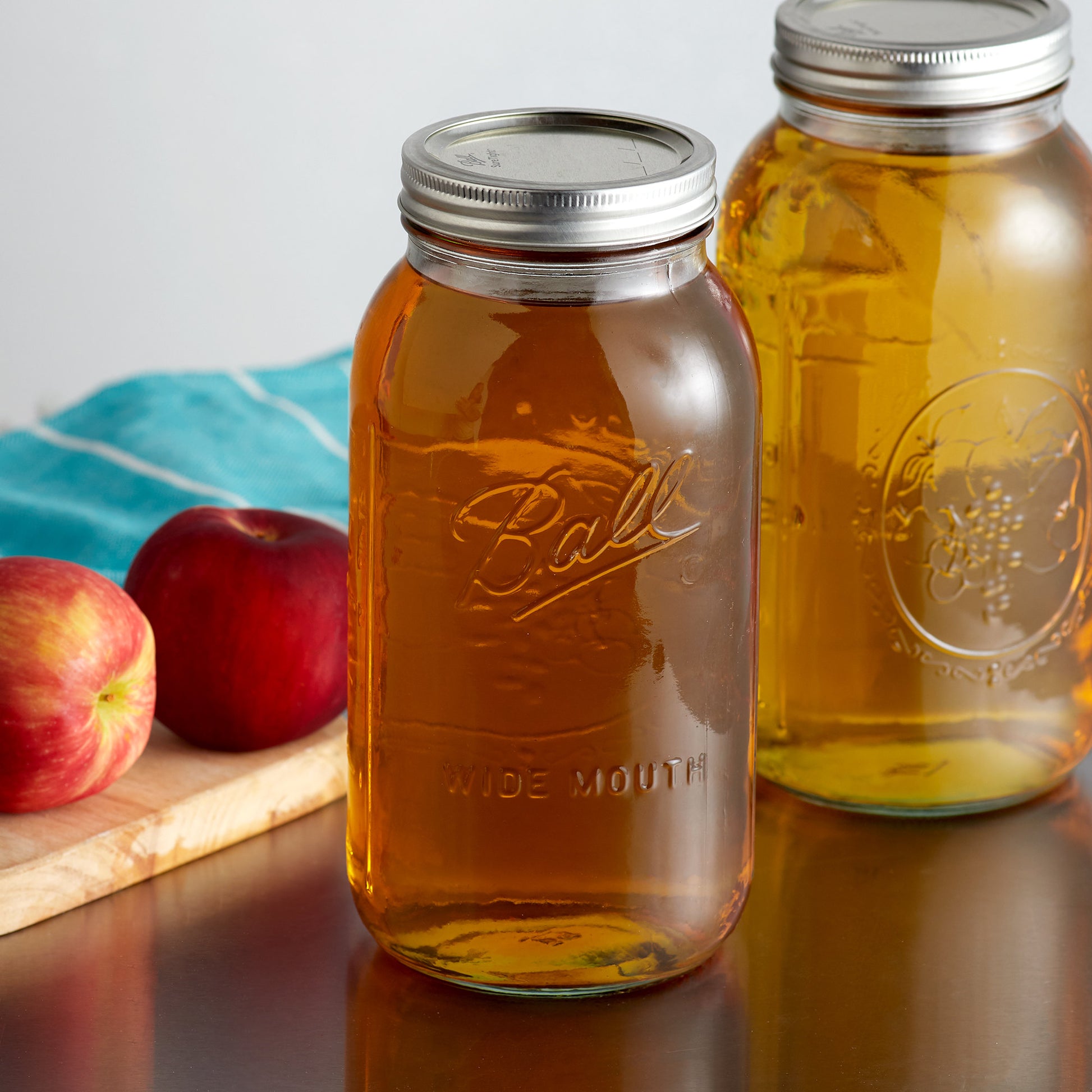Two Ball jars containing freshly made apple cider on a countertop