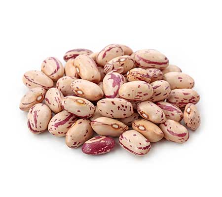 A heap of heirloom pinto beans scattered on a white surface